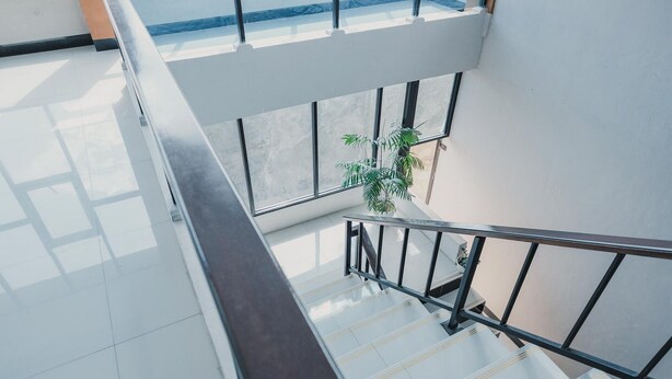 A modern interior with a glass railing, a staircase, and a potted plant. - RedDoorz Syariah near Balai Kota Bengkulu (Bengkulu)