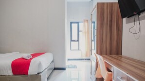 A hotel room with a bed, a desk, a chair, and a television. - RedDoorz Syariah near Balai Kota Bengkulu (Bengkulu)