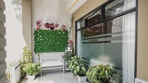 A reception area with a white bench, potted plants, a green wall with flowers, and a glass door with a sign reading "Grand Mentari". - RedDoorz Syariah near Balai Kota Bengkulu (Bengkulu)
