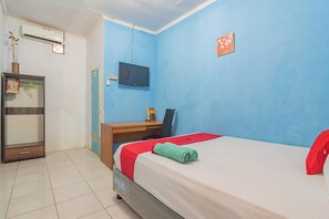 Una habitación de hotel con cama, escritorio, televisor y armario.