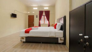 A hotel room with a bed, a wardrobe, a television, and a window with curtains.