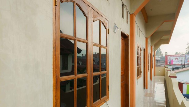 A corridor with large wooden-framed windows and a tiled floor.
