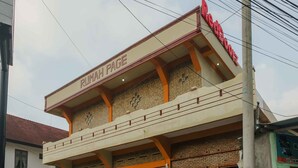 A building with a sign reading "Rumah Page" and a sign for "RocoRocoZ" on the right.