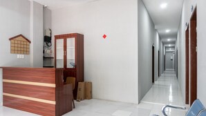 Un área de recepción con un mostrador de madera, un pequeño espacio de asientos y un pasillo que conduce a otras habitaciones.