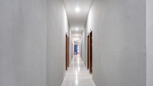 Un pasillo largo y estrecho con suelo de baldosas blancas y paredes de color claro.