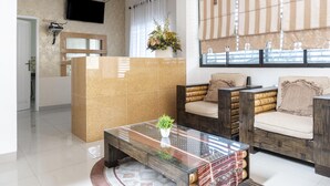 A modern lobby with a reception desk, seating area, and a large window with striped curtains. - RedDoorz Syariah near Stadion Teladan Medan (Medan)