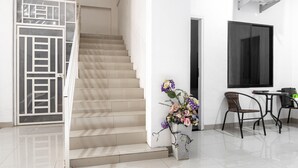 A staircase leading to a landing, a dining area with a table and chairs, and a decorative vase with flowers. - RedDoorz Syariah near Stadion Teladan Medan (Medan)