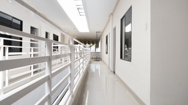 A corridor with white railings, a polished floor, and a skylight. - RedDoorz Syariah near Stadion Teladan Medan (Medan)
