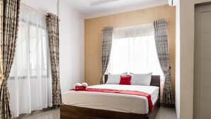 A hotel room with a large bed, two windows with sheer curtains, a wooden headboard, and a red throw blanket. - RedDoorz Syariah near Stadion Teladan Medan (Medan)