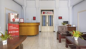 A reception area with a RedDoorz sign, a reception desk, and a reception counter.