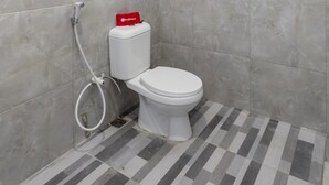 A bathroom with a toilet, a bidet, and a shower hose.