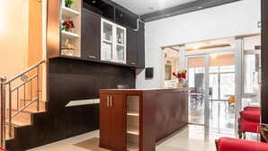 A modern kitchen with dark cabinetry, a central island, and a staircase leading to an upper level. - RedDoorz near Manhattan Times Square Medan 2 (Medan)