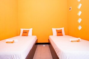 A hotel room with two beds, each with a white bedspread and an orange pillow labeled "KOOL KOST". - KoolKost Syariah near Transmart Tegal (Tegal)