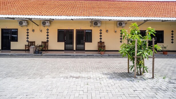 A building with a tiled roof, air conditioning units, and potted plants. - KoolKost Syariah near Transmart Tegal (Tegal)