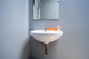 A white wall-mounted sink with a mirror above it and a "Kool Kost" soap dispenser to the right. - KoolKost Syariah near Transmart Tegal (Tegal)