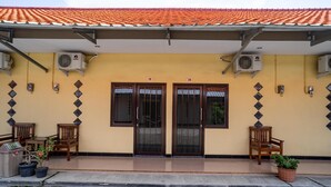 A building with two doors marked 19 and 20, air conditioning units, and potted plants. - KoolKost Syariah near Transmart Tegal (Tegal)