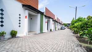 A row of modern, single-story buildings with a brick-paved pathway. - KoolKost Syariah near Transmart Tegal (Tegal)