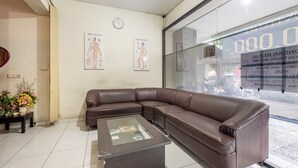 A reception area with a brown leather sofa, a glass-top coffee table, and a wall clock.