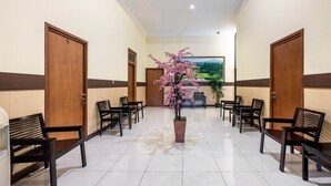 A hotel lobby with a central floral arrangement, wooden doors, and rows of seating.