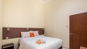 A hotel room with a bed, a wooden headboard, a nightstand, and a wardrobe.