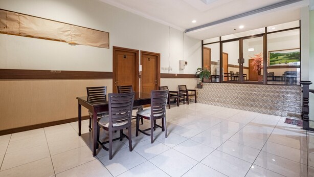 A hotel lobby with a dining area, wooden doors, and a view of the outdoors.