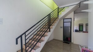 Eine Treppe mit Holzboden und schwarzen Geländern, die zu einem Raum mit grüner Wand und einer Tür führt.