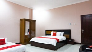 A hotel room with a large bed, a wardrobe, and a bedside table.