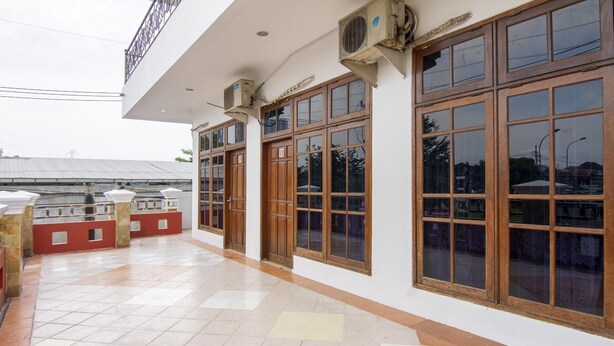 A building with large windows and air conditioning units, a tiled floor, and a balcony area. - RedDoorz Plus @ Gunungsari Surabaya (Surabaya)