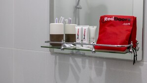Kylpyhuoneen hyllyllä on hygieniatarvikkeita, kuten Red Doorz -merkkinen kosmetiikkapussi, hammasharjat ja kuppi.