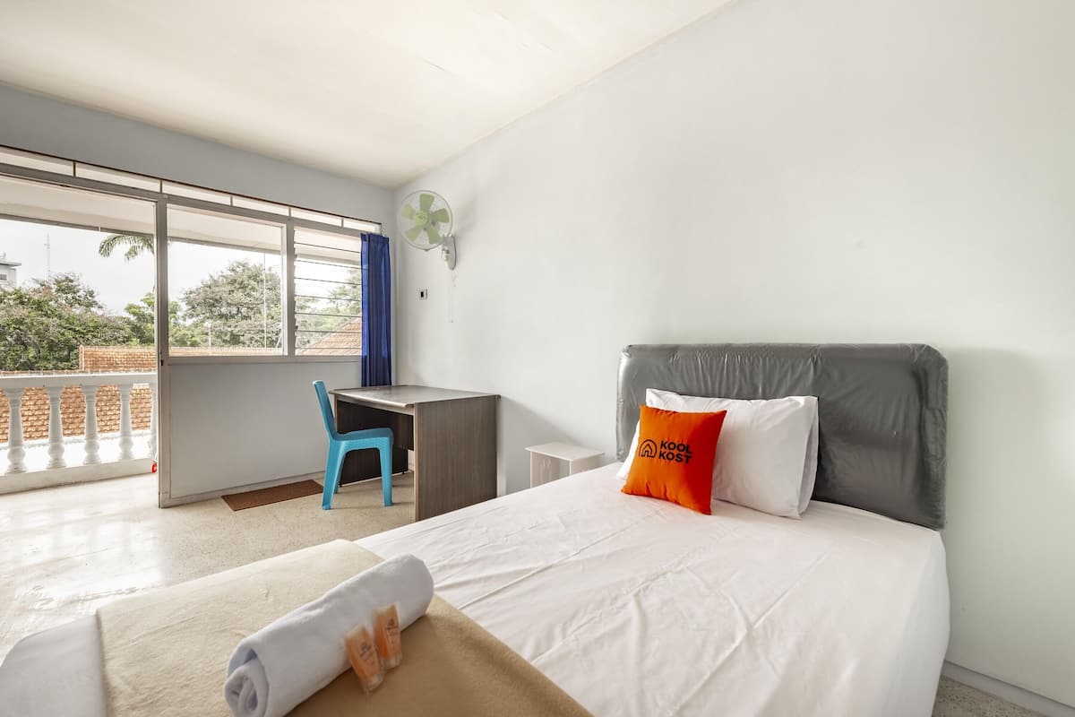 A hotel room with a bed, a desk, a chair, a window, and a balcony.