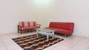 A living room with two sofas, a glass coffee table, and a patterned rug.