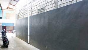 A motorcycle parked in a covered parking area with a concrete wall and a metal roof. - RedDoorz near Sentani Airport Jayapura (Sentani)