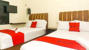 Dos camas individuales con ropa blanca y cabeceros rojos, cada una con una almohada de RedDoorz y una toalla enrollada.