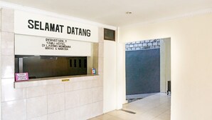 A reception area with a sign reading "SELANGAT DATANG" and "PERHATIAN TAMU HOTEL DI LARANG MEMBAWA MIRAS & NARKOBA". - RedDoorz near Sentani Airport Jayapura (Sentani)