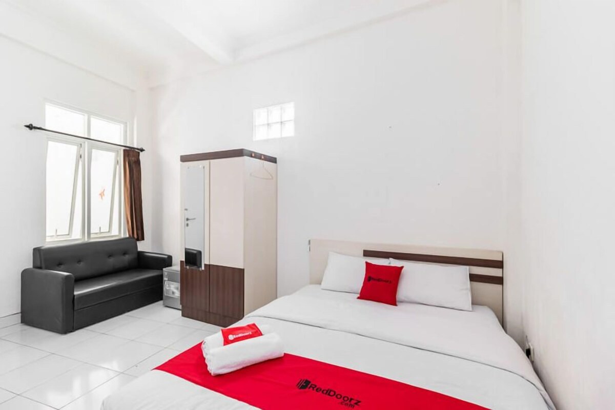 Una habitación de hotel con cama, sofá, armario y ventana.