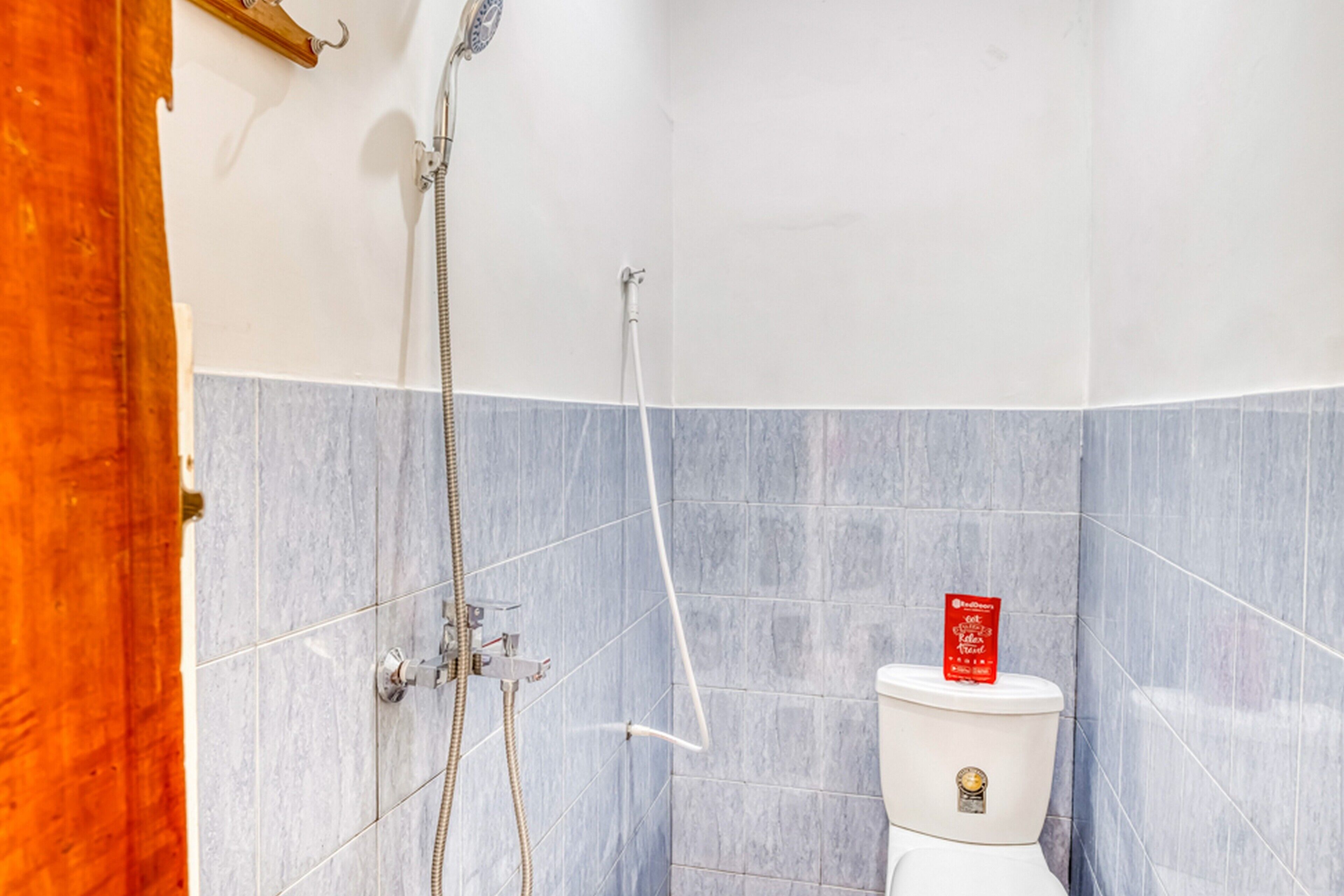 Een badkamer met een douche, toilet en een houten deur.