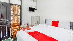 A hotel room with a bed, a TV, a wardrobe, and a window with curtains. - RedDoorz near Wisata Pantai Parangtritis (Parangtritis)