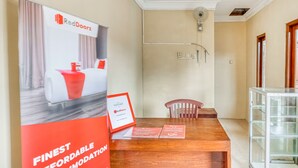 A hotel reception area with a wooden desk, a glass display case, and a poster advertising RedDoorz. - RedDoorz near Wisata Pantai Parangtritis (Parangtritis)