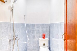 A bathroom with a white toilet, a shower, and a blue-tiled wall.