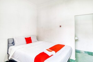 A hotel room with a bed, white walls, and a green-tiled floor.