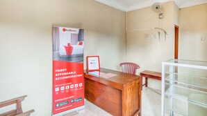 A reception desk with a red advertisement for RedDoors, a wooden bench, a glass display case, and a shower area. - RedDoorz near Wisata Pantai Parangtritis (Parangtritis)
