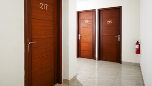A hallway with two wooden doors labeled 216 and 215, and a fire extinguisher on the wall. - RedDoorz near Palembang Trade Center 3 (Palembang)