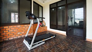 A treadmill in a room with a brick wall and large windows. - RedDoorz near Palembang Trade Center 3 (Palembang)