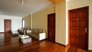 A spacious living room with a sofa, a coffee table, and two wooden doors. - RedDoorz near Palembang Trade Center 3 (Palembang)