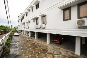 A multi-story residential building with a covered parking area.