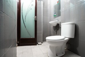 A modern bathroom with a toilet, sink, and frosted glass door.
