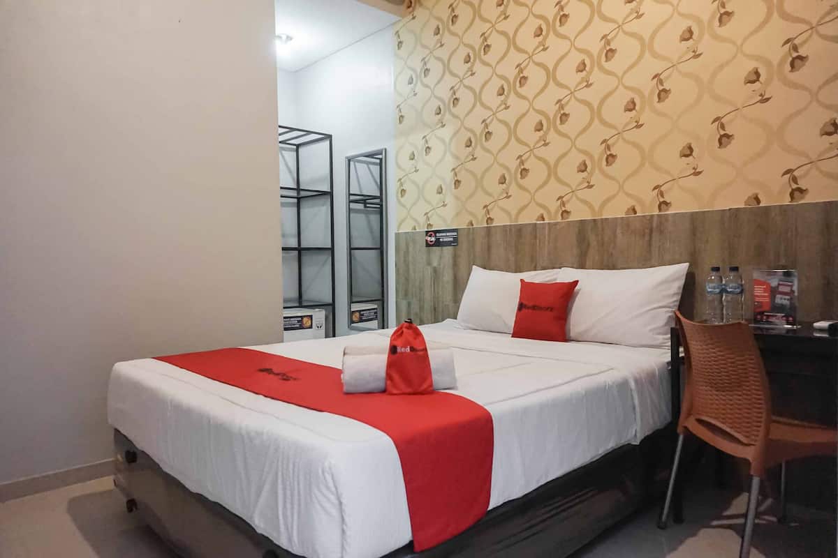 A hotel room with a bed, a chair, and a desk.