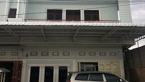 A multi-story building with a white facade, multiple balconies, and a car parked in front. - RedDoorz near CitraLand Gama City Medan (Medan)