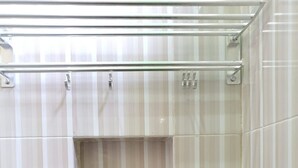 A bathroom with striped tiles, a glass shower enclosure, and a soap dispenser. - KoolKost Syariah @ Medan Johor (Medan)