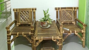 A bamboo furniture set with a central table and two chairs, a potted plant on the table, and a green wall in the background. - KoolKost Syariah @ Medan Johor (Medan)